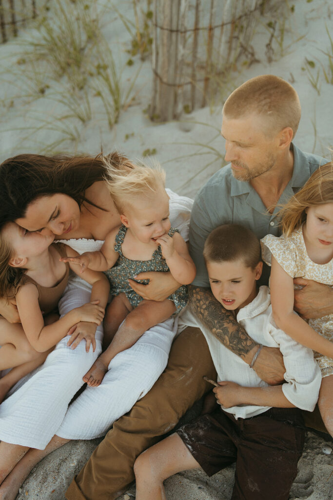 a large family of six snuggles together on wrightsville beach in north carolina for some lifestyle storytelling photos during a fully styled family photoshoot